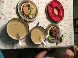 left over garlic soup with a side of chicken quesadilla or cauliflower grilled cheese with shredded pork, rice and beans for the kids on a messy dinner table 